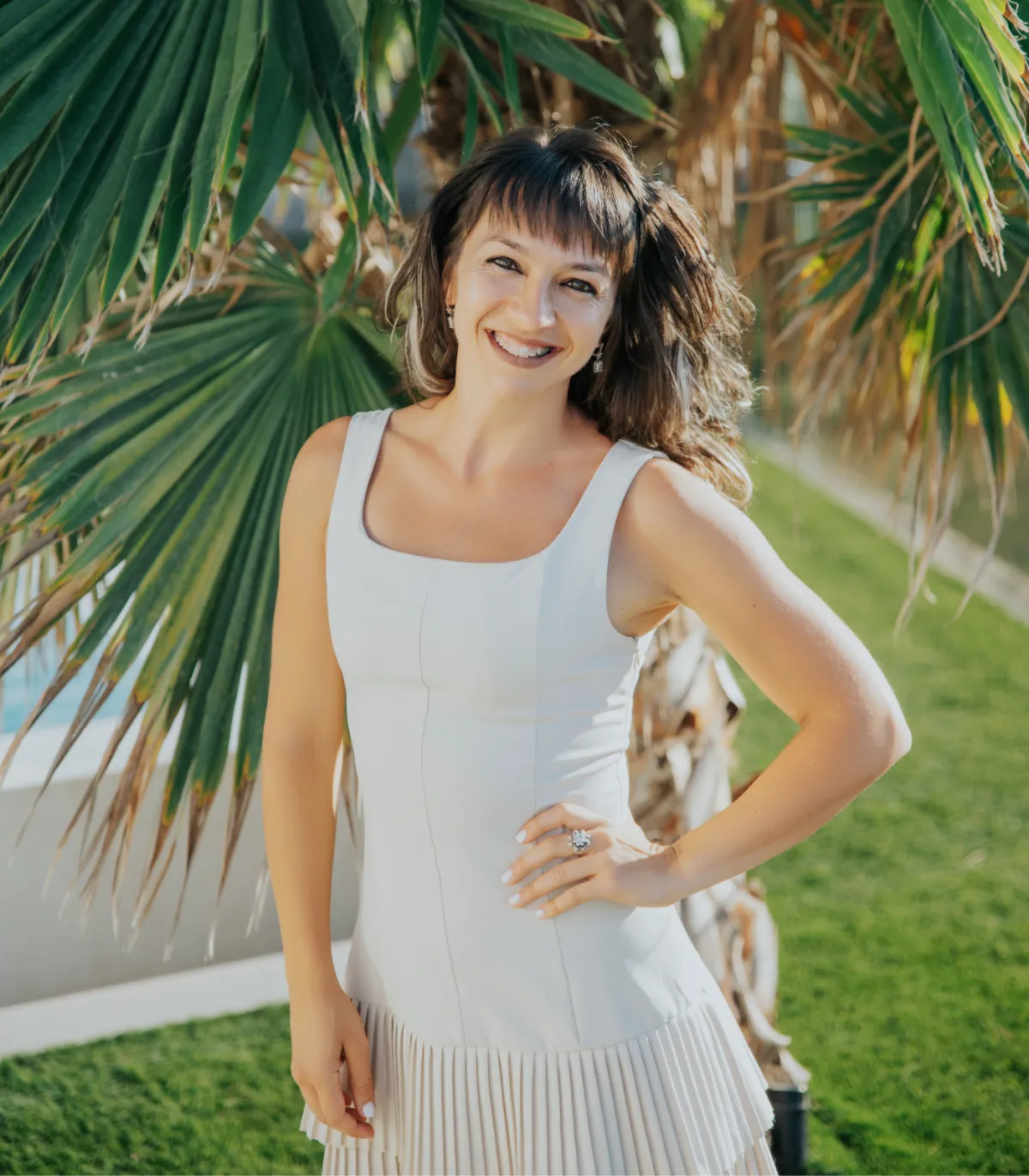 Marchela in a white dress under palm trees